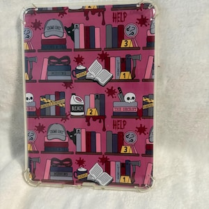 May include: Clear protective case with a repeating pattern of crime scene elements on a pink background. The design includes books, skulls, axes, and the words "CRIME UNIT", "MISSING", "HELP", and "THE SECRET".