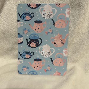 May include: A blue and white teacup and teapot pattern on a light blue background. The teacups and teapots are decorated with pink and blue polka dots and floral designs.