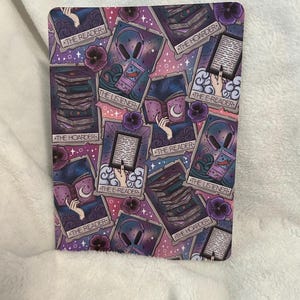 May include: A repeating pattern of tarot cards with a purple, pink and blue colour scheme. The cards feature illustrations of books, headphones and hands holding books. The text on the cards reads "The Reader", "The Listener", "The Hoarder", and "The E-Reader".
