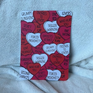 Op de afbeelding: Rode hartvormige kaarten met witte tekst, elke kaart heeft een andere relatie status of type liefde. De kaarten omvatten: Grumpy Sunshine, Enemies to Lovers, One Bed, Lovers Who Hurt You, Secret Identity, Age Gap, Trigger Warning, Fake Dating, Forced Proximity, Opposites Attract, Slow Burn, Love Triangle, Mutual Pining, Grumpy Sunshine, Friends to Lovers, Forbidden Love, Trigger Warning, Who Hurt You, Second Chances, Secret Identity, Forced Proximity, Age Gap, Enemies to Lovers, One Bed, Fake Dating.