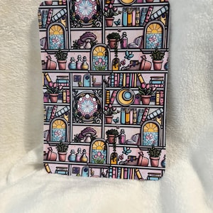 Könnte beinhalten: Eine rechteckige Karte mit einem fantasievollen Bücherregal-Design. Die Regale sind mit Büchern, Topfpflanzen und dekorativen Elementen gefüllt. Die Farbpalette umfasst Rosa, Gelb und Blau und schafft eine lebendige und einladende Ästhetik.