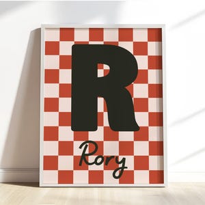 Puede incluir: Impresi&oacute;n art&iacute;stica enmarcada con una gran letra negra "R" sobre un fondo a cuadros rojo y crema. El nombre "Rory" est&aacute; escrito en cursiva debajo de la letra. La obra de arte se presenta en un marco blanco.