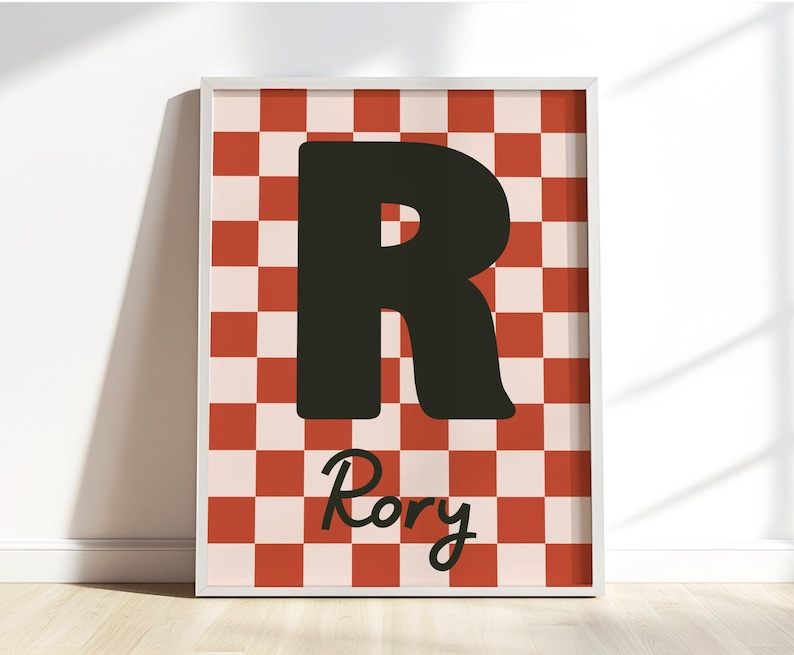 Puede incluir: Impresi&oacute;n art&iacute;stica enmarcada con una gran letra negra "R" sobre un fondo a cuadros rojo y crema. El nombre "Rory" est&aacute; escrito en cursiva debajo de la letra. La obra de arte se presenta en un marco blanco.
