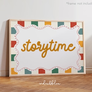 Könnte beinhalten: Gerahmter Druck mit dem Wort "storytime" in senfgelber Schrift. Der Druck hat einen weißen Hintergrund mit einem dekorativen Rand aus roten, grünen, gelben und blauen Quadraten. Der Rahmen hat eine helle Holzfarbe.