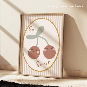 May include: Framed print with a cartoon illustration of two cherries with smiling faces and the text "So Sweet." The cherries are brown with light green stems, set against a cream background with vertical stripes.