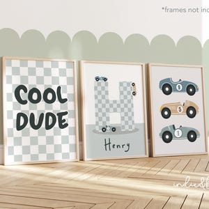 May include: Three framed prints with a racing car theme. The first print has a chequered background and the text "COOL DUDE". The second print has a chequered letter "H" with a racing car on top and the name "Henry" below. The third print has three racing cars with numbers 9, 5, and 1.