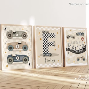 May include: Three framed prints with a racing theme. The prints feature illustrations of race cars, the letter "F" in a checkered pattern, and the words "Little Racer" and "Finley". The color palette includes beige, grey, and blue.