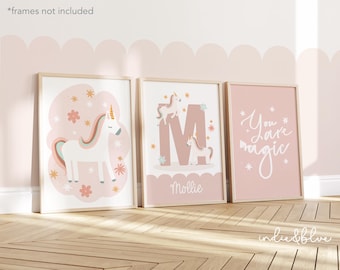 May include: Three pink framed prints with unicorn illustrations. The first print features a white unicorn with a rainbow mane and tail. The second print features a pink letter M with a unicorn on each side. The third print features the text "You are magic" in white cursive.