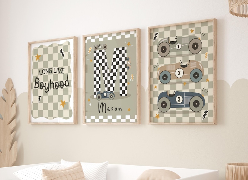 May include: Three framed prints with a racing car theme. The first print has a chequered background and the text "Long Live Boyhood". The second print has a chequered "M" with a racing car in front of it and the name "Mason" below. The third print has a chequered background with three racing cars stacked on top of each other.