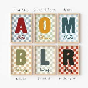 Puede incluir: Seis impresiones enmarcadas con letras grandes y nombres. Cada impresi&oacute;n presenta una combinaci&oacute;n de colores diferente y un fondo a cuadros. Las letras son en rojo, mostaza, azul, oliva, gris y negro. Los nombres incluyen Arlo, Oliver, Milo, Barney, Lucas y Rory.