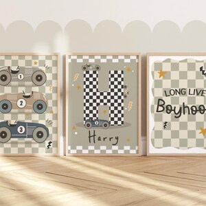 May include: Three framed prints with a chequered background and racing car illustrations. The first print features three racing cars with the numbers 1, 2, and 3. The second print features a chequered letter H with a racing car and the name Harry. The third print features the text "Long Live Boyhood".