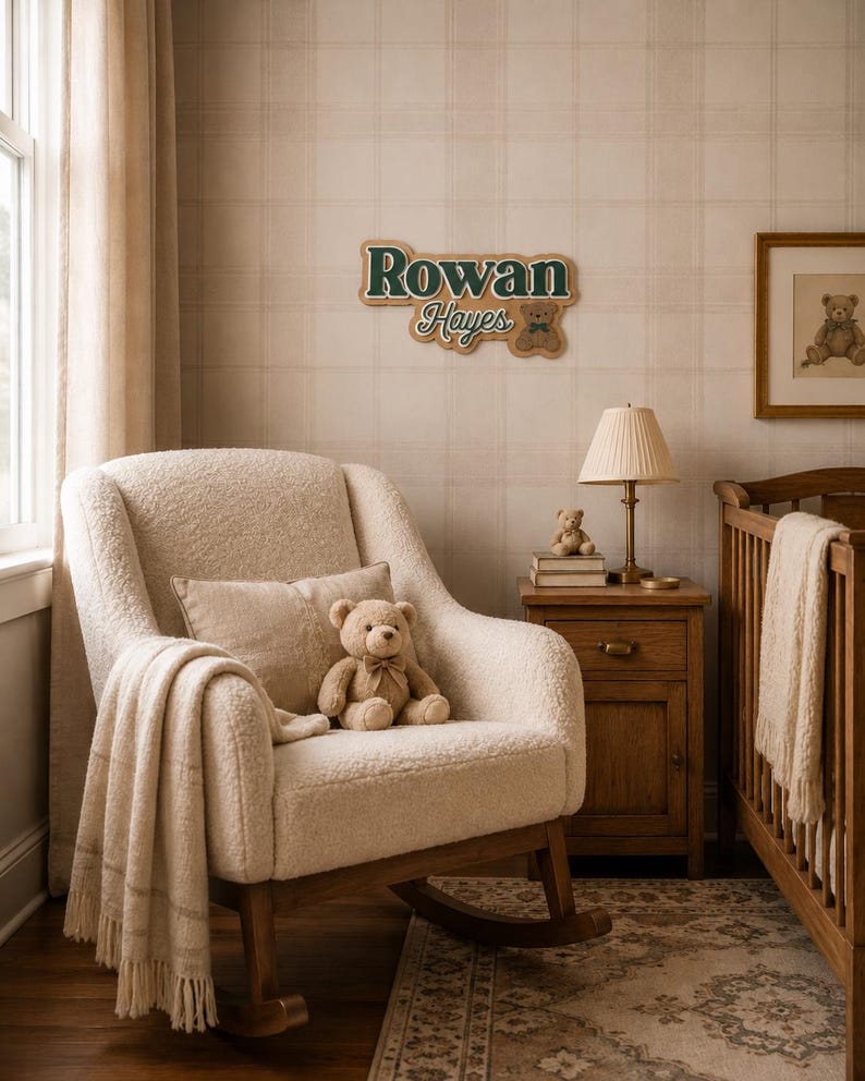 Puede incluir: Un cuarto de beb&eacute; con una mecedora color crema, una cuna de madera y una mesita de noche. Un osito de peluche est&aacute; sentado en la silla, y un letrero en la pared dice "Rowan Hayes". La habitaci&oacute;n tiene una paleta de colores suaves y neutros con una alfombra en el suelo.