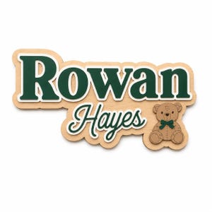 Puede incluir: Letrero de nombre de madera con el nombre "Rowan Hayes" en verde con un contorno blanco. Un peque&ntilde;o oso de peluche con pajarita verde est&aacute; a la derecha. El letrero es de madera clara.