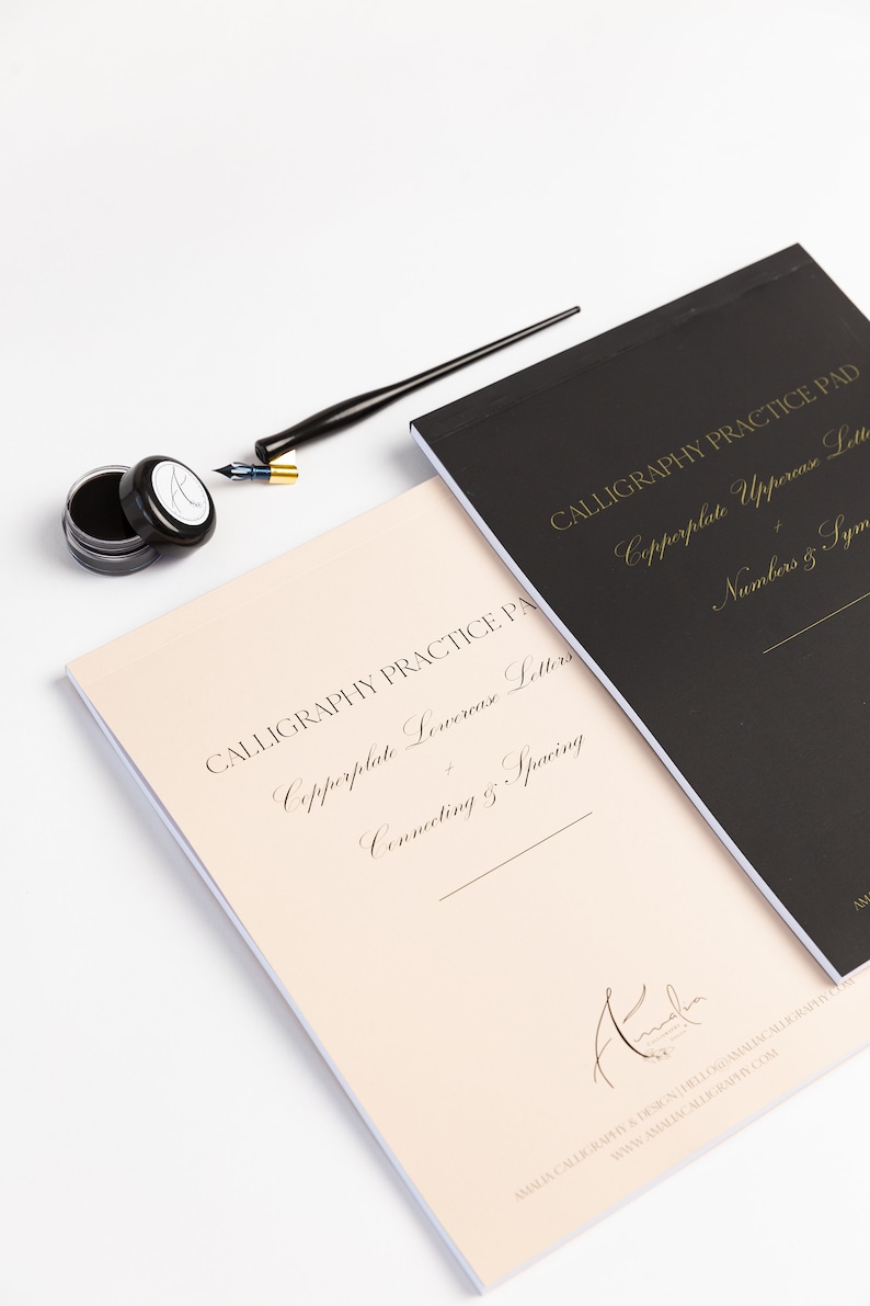 May include: Two calligraphy practice pads, one with a black cover and the other with a cream cover. The black pad features the text "Copperplate Uppercase Letters, Numbers & Symbols" in gold lettering. The cream pad features the text "Copperplate Lowercase Letters, Connecting & Spacing" in gold lettering. Both pads have the text "Calligraphy Practice Pad" in gold lettering.