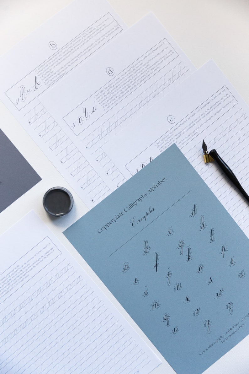 May include: A blue sheet of paper with the title "Copperplate Calligraphy Alphabet Exemplar" and a grid of lowercase letters written in copperplate calligraphy.