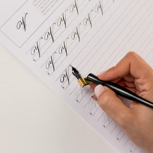 May include: A person practicing calligraphy with a black and gold calligraphy pen on a lined paper. The paper has the letter 'W' written at the top and several lines of the letter 'W' written below.
