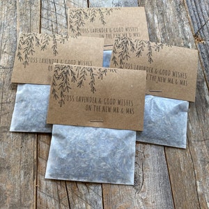 May include: Kraft paper sachets filled with lavender, each with a printed message: "TOSS LAVENDER & GOOD WISHES ON THE NEW MR & MRS." The sachets are arranged on a rustic wooden surface, ideal for weddings or special events.