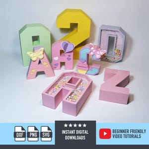May include: A collection of colorful papercraft letters and numbers. The letters are pink, green, and gray, some decorated with butterflies and hearts. The number 2 is yellow. The image also includes the text "INSTANT DIGITAL DOWNLOADS" and "BEGINNER FRIENDLY VIDEO TUTORIALS."