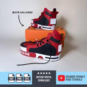 Op de afbeelding: Twee rode, zwarte en witte high-top sneakers worden getoond, een bovenop een oranje doos, de andere ervoor. De sneakers hebben zwarte veters en een witte zool. De tekst "BOTH INCLUDED" staat erboven. Hieronder staan iconen en tekst.