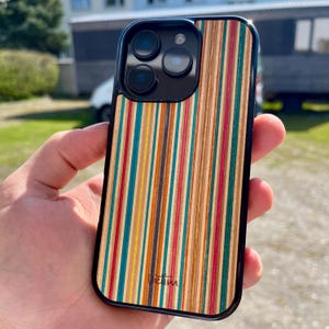 May include: A black phone case with a colorful wood grain pattern. The case has a black border and a small logo that says "Victim".