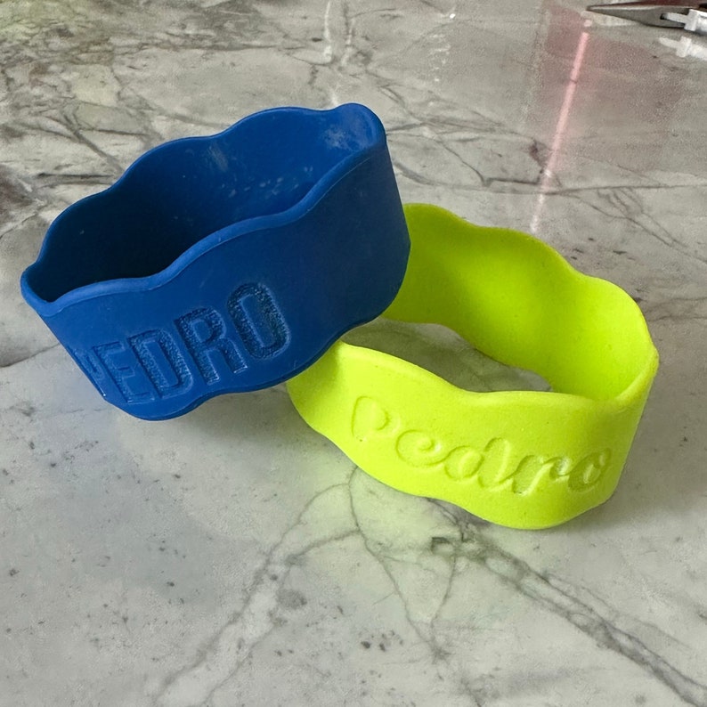 K&ouml;nnte beinhalten: Zwei Silikon-Armb&auml;nder mit dem Namen "Pedro" in Pr&auml;gung. Die Armb&auml;nder sind blau und gr&uuml;n.