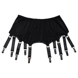 Peut inclure: Jarretelles noires avec six bretelles réglables et des fermoirs métalliques. La ceinture est ornée d'une bordure en dentelle festonnée sur le bord supérieur. Les bretelles sont en matière noire lisse.