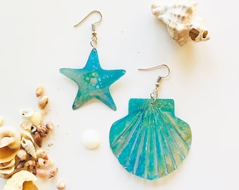 Könnte beinhalten: Ein Paar blaue und grüne Harzohrringe mit einem Stern- und Muschelmotiv.