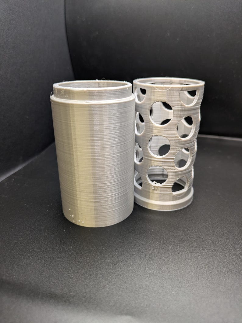 Puede incluir: Dos contenedores cil&iacute;ndricos impresos en 3D. Uno es s&oacute;lido y el otro tiene un patr&oacute;n de agujeros.
