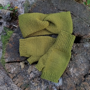 May include: Olive green knitted headband and fingerless gloves set. The headband has a twisted design, and the gloves have ribbed cuffs. The set is made of a textured knit fabric, perfect for cooler weather.