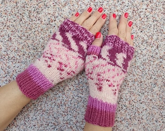 May include: A pair of fingerless gloves featuring a knitted pattern in shades of cream, light pink, and dark magenta. The gloves have ribbed cuffs at the wrists and knuckles, with a distinct color-blocked design and a textured knit construction.