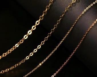 May include: Three gold chains of different lengths, all made of small, oval-shaped links.