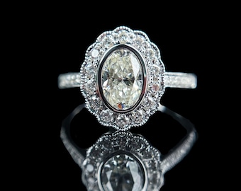 May include: A diamond ring with an oval-cut center stone, surrounded by a halo of smaller diamonds. The ring has a detailed, ornate setting and a band with additional diamond accents. The ring is set against a black background, with the text "1.01CT I VS2 EX VG N" at the bottom.