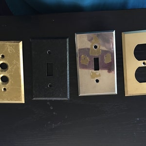 Peut inclure: Quatre plaques murales électriques différentes, deux sont dorées, une est noire et une est argentée. Les plaques dorées ont un interrupteur simple et une double prise.