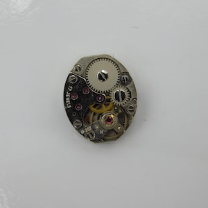 May include: A silver watch movement with 17 jewels and a visible gear system. The movement is circular and has a silver finish.