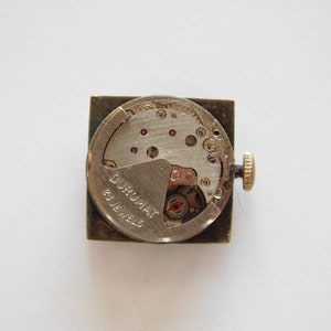 Könnte beinhalten: Nahaufnahme der Rückseite einer silbernen Uhr mit der Aufschrift DUROMAT 15 JEWELS.