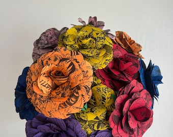 May include: A bouquet of paper flowers crafted from comic book pages. The roses feature vibrant colors including orange, yellow, red, purple, and blue, with black ink illustrations and text bubbles visible on each petal throughout the arrangement.