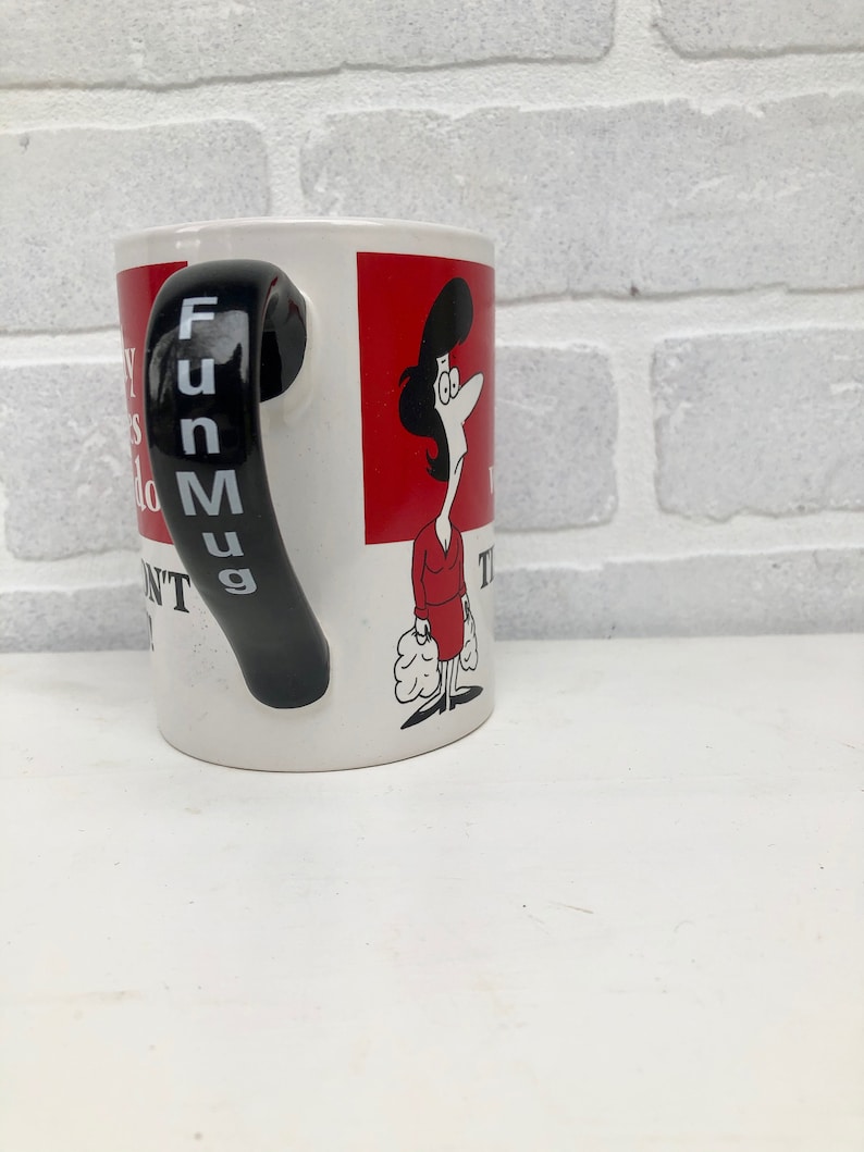 Op de afbeelding: Witte keramische mok met een zwarte handgreep met verticaal de tekst "Fun Mug". De mok heeft een cartoonillustratie van een vrouw in een rode jurk en een rode achtergrond. De mok heeft tekst.
