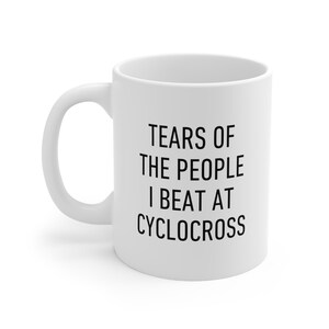 Może przedstawiać: Biały ceramiczny kubek do kawy z czarnym tekstem, który brzmi "Tears of the people I beat at Cyclocross".