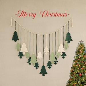 Può includere: Un muro bianco con una ghirlanda di alberi di Natale in filato verde e bianco appesa. La ghirlanda dice "Buon Natale" in corsivo rosso. Un albero di Natale decorato è sullo sfondo.