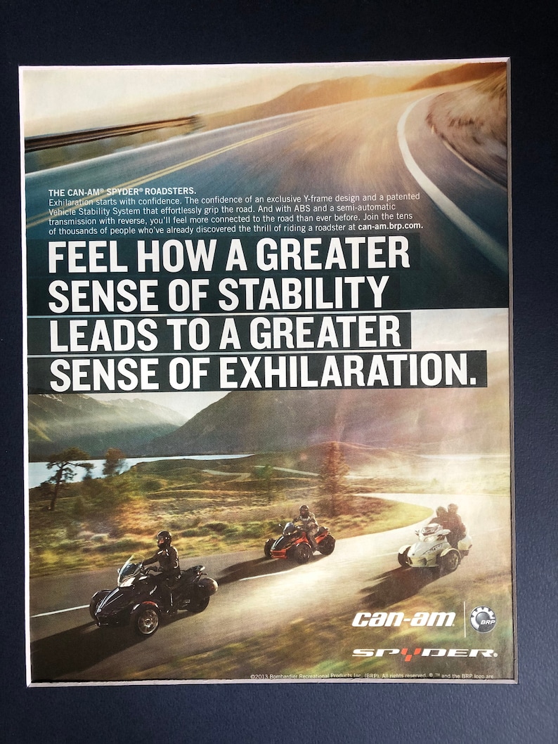 May include: A Can-Am Spyder Roadster motorcycle advertisement featuring a black and red motorcycle on a winding road. The text reads "Feel how a greater sense of stability leads to a greater sense of exhilaration."