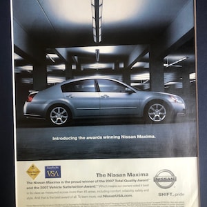 May include: A silver Nissan Maxima car is shown in a parking garage. The car is the proud winner of the 2007 Total Quality Award and the 2007 Vehicle Satisfaction Award. The text "SHIFT_pride" is shown in the bottom right corner of the image.