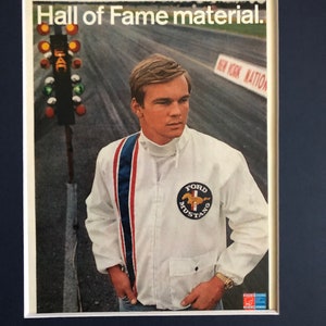 May include: A vintage advertisement for Ford Mustang featuring a young man wearing a white jacket with a blue, red, and white stripe down the sleeve and a Ford Mustang logo on the chest. The text "Hall of Fame material." is at the top of the image.