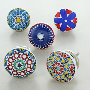 May include: Five ceramic cabinet knobs with different geometric patterns. The knobs are in shades of blue, red, yellow, and green.