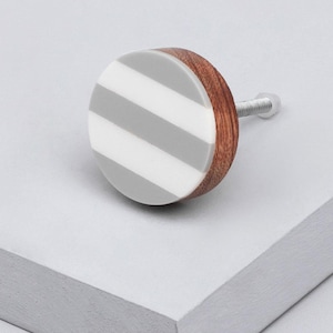 May include: A round grey and white striped cabinet knob with a brown wood base and a silver screw.