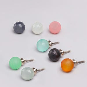 Può includere: Una collezione di pomelli per mobili sferici e sfaccettati in vari colori, tra cui grigio, bianco, rosa, verde acqua, nero, verde, arancione e verde chiaro. Ogni pomello ha una vite color argento. Questi pomelli decorativi sono adatti per mobili.