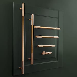 Peut inclure: Ensemble de quincaillerie de placard dorée, comprenant de longues poignées et des poignées plus courtes, montées sur une porte vert foncé. La quincaillerie présente une prise texturée et un design élégant et moderne.