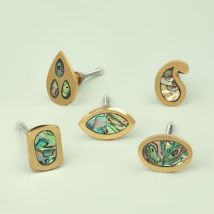 May include: Five brass cabinet knobs with iridescent abalone shell inlays. The knobs are in various shapes, including a teardrop, oval, and paisley.