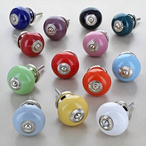 May include: A collection of colorful ceramic cabinet knobs. The knobs are round with a glossy finish and a silver-colored metal base. Colors include blue, purple, black, green, red, pink, orange, yellow, and white. Each knob has a decorative floral design.