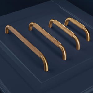 Può includere: Quattro maniglie per mobili in ottone con un'impugnatura strutturata a motivo diamantato. Le maniglie hanno un design curvo e sono poste su uno sfondo blu scuro. Queste maniglie decorative sono adatte per cassetti e armadi.
