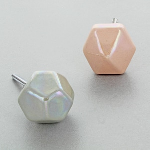 Peut inclure: Deux boutons de cabinet en céramique irisée de formes géométriques. L'un est un hexagone rose clair et l'autre est une forme gris clair à plusieurs côtés.